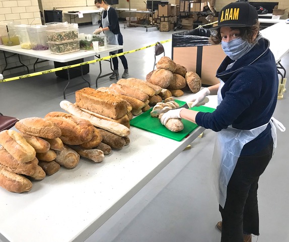 Volunteer slicing bread at food kitchen